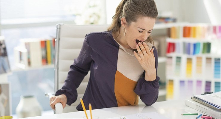 A0004_486625819 woman sitting at desk yawning