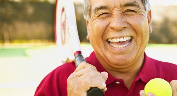 0076_76801403 man smiling holding a tennis racket and tennis ball