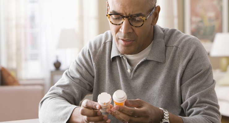 0088_476804937 man reviewing two medication bottles