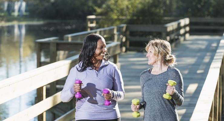 0024_496836419 two women walkng on a foot bridge with hand weights