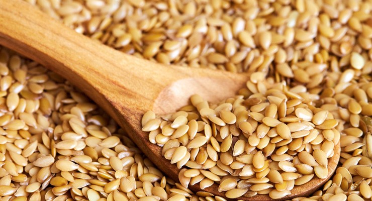 Closeup of golden sesame seeds with wooden spoon wooden spoon in pile of sesame seeds