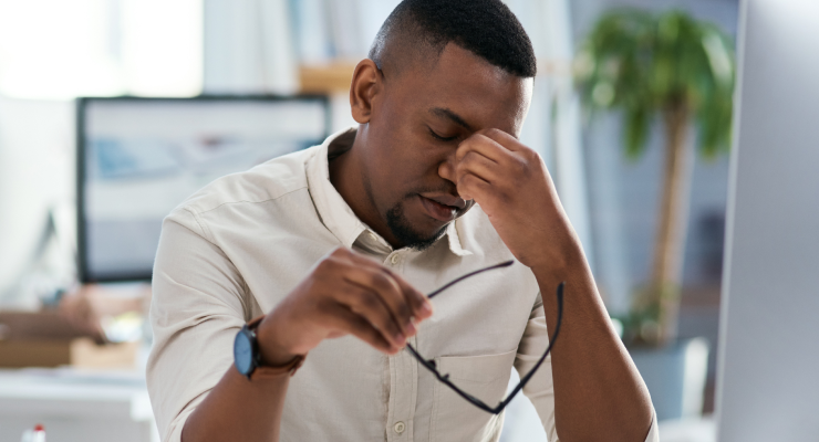 0083_headache_1325363443_740x400 man holding glasses, pinching bridge of nose.