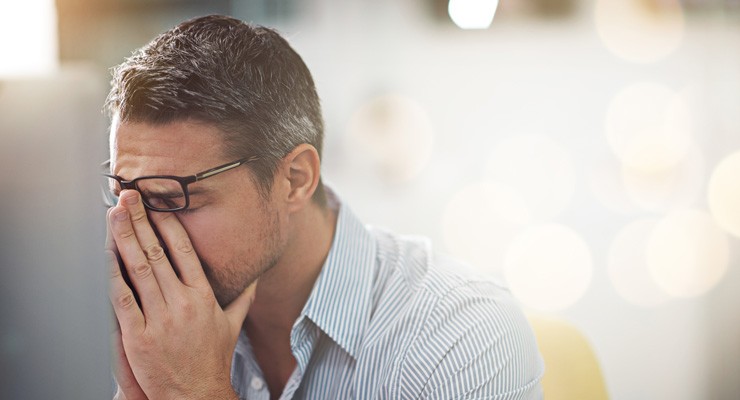 stressed man rubbing his eyes with his fingers